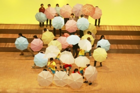ステージで傘を広げる役者たちの写真