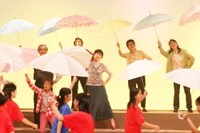 傘をさして踊る役者たちの写真