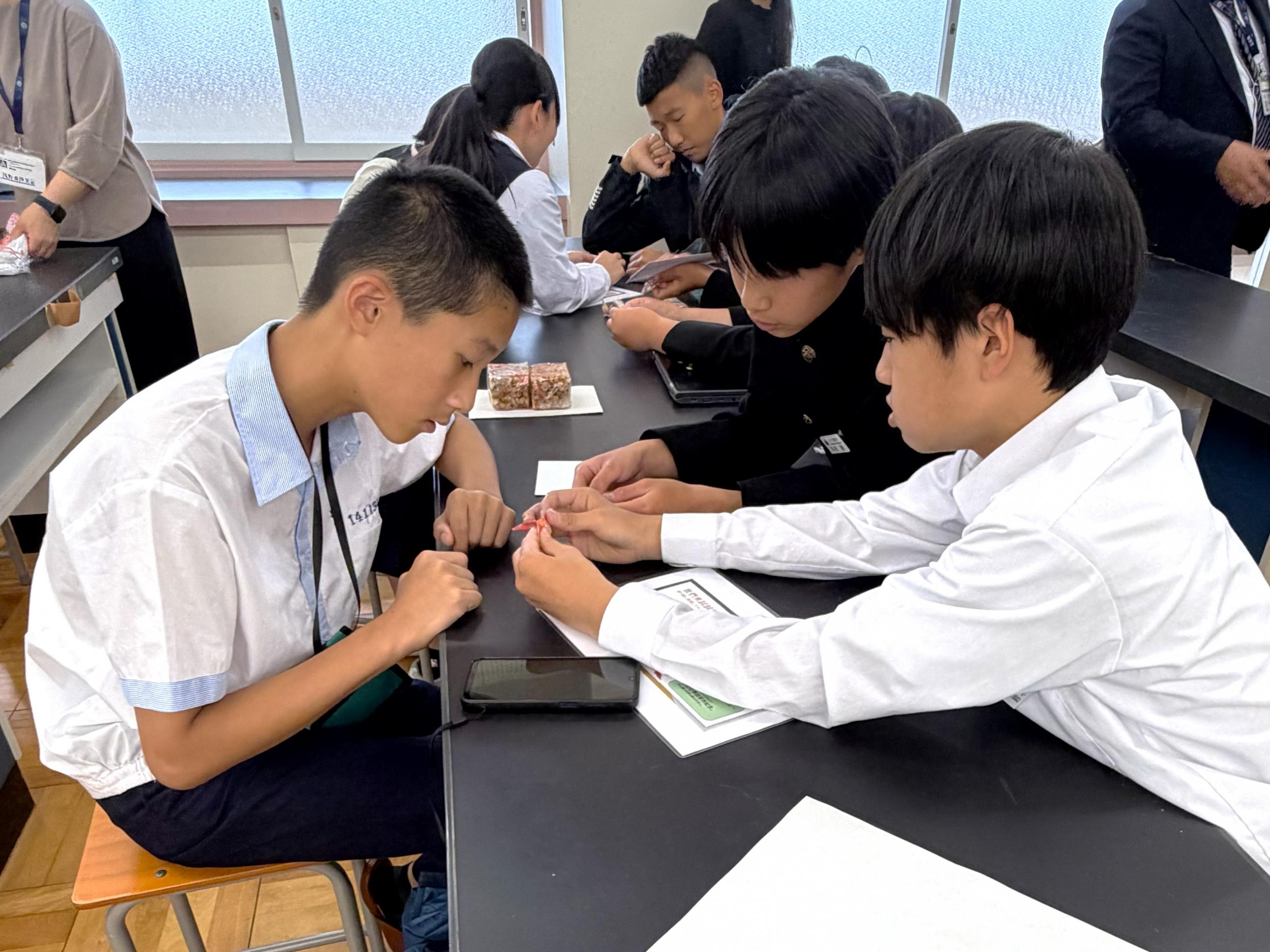 淡水国民中学生徒(左)がバディと一緒に折り紙体験
