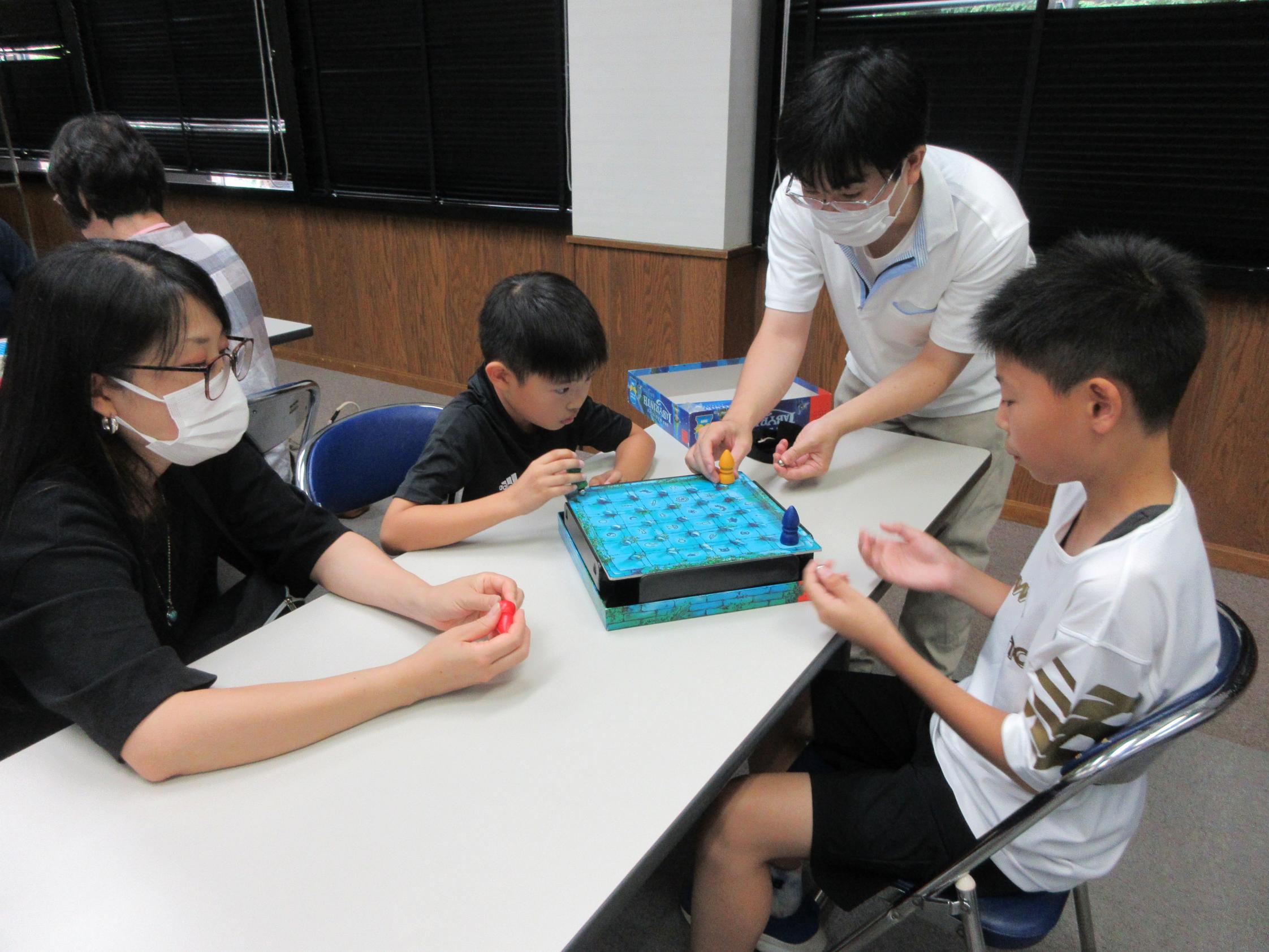 講師の先生に教えてもらってボードゲームをしている様子